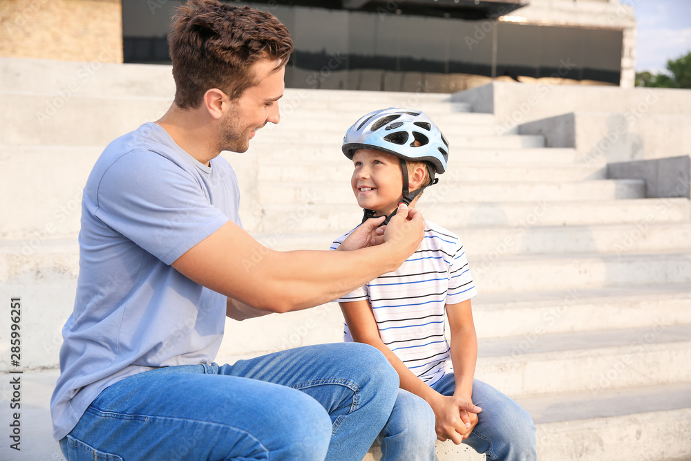 父亲在户外骑自行车前帮儿子戴上头盔