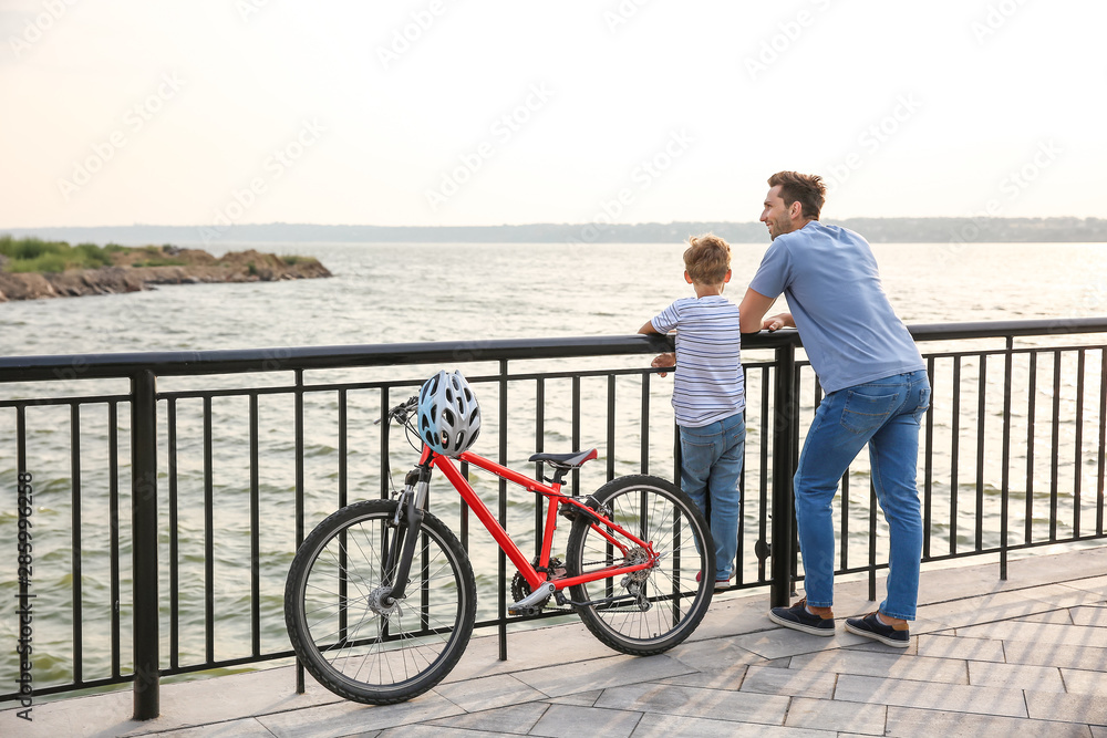 父亲和他的小儿子在河边骑自行车
