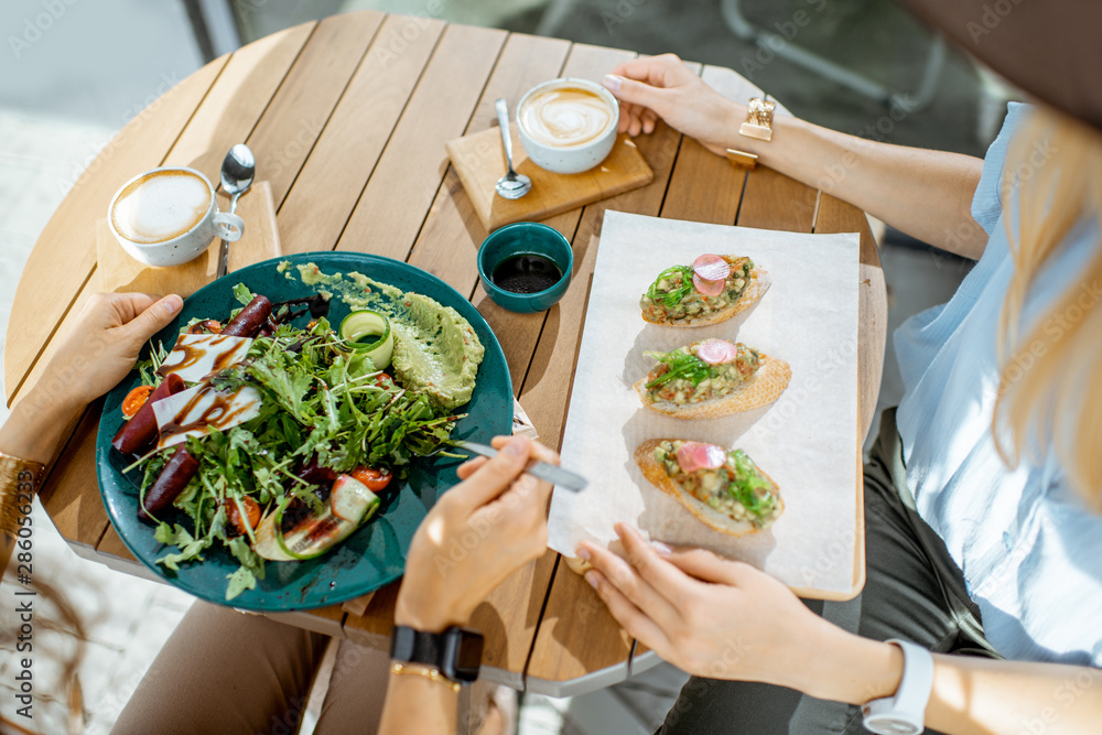 女性在咖啡馆吃健康素食，桌子上方特写