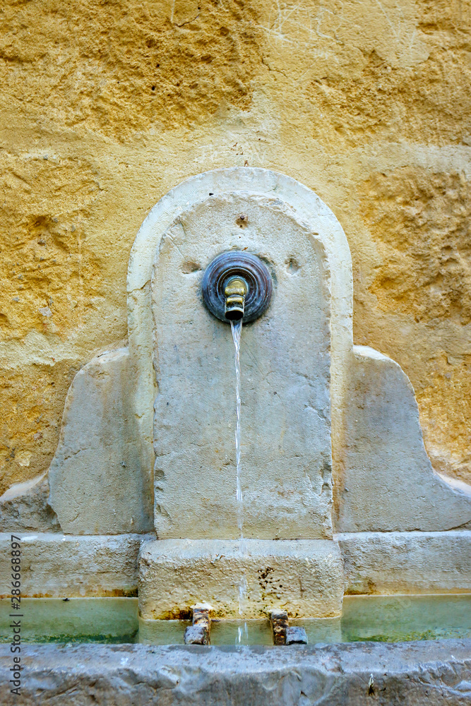 stone fountain in mediterranean village with historical building 