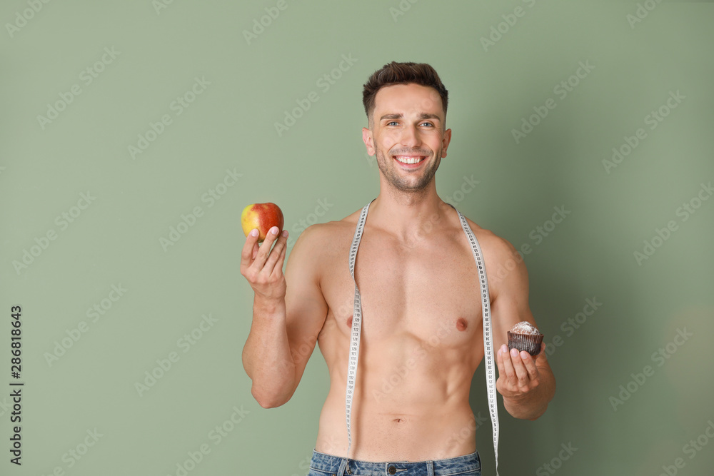 带着卷尺、甜点和苹果的英俊肌肉男。减肥概念