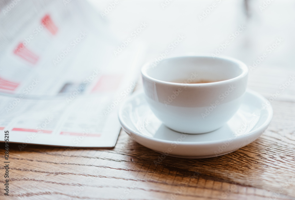 大c旁边的木桌上放着一杯黑咖啡和新鲜的运动报纸的静物图像
