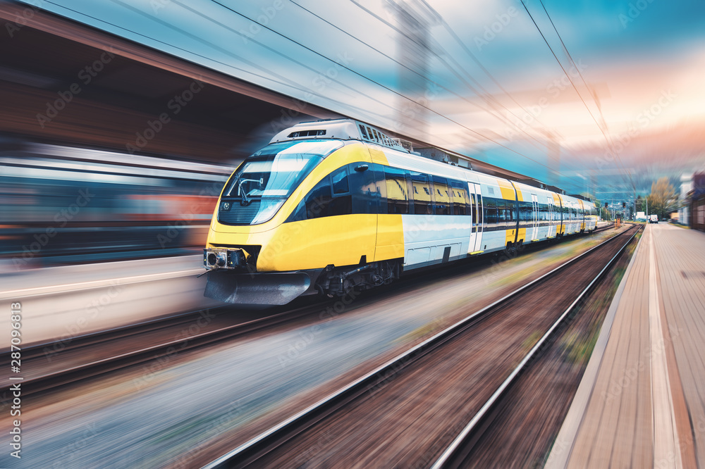 日落时分，高速黄色列车在火车站上行驶。现代城际客运列车