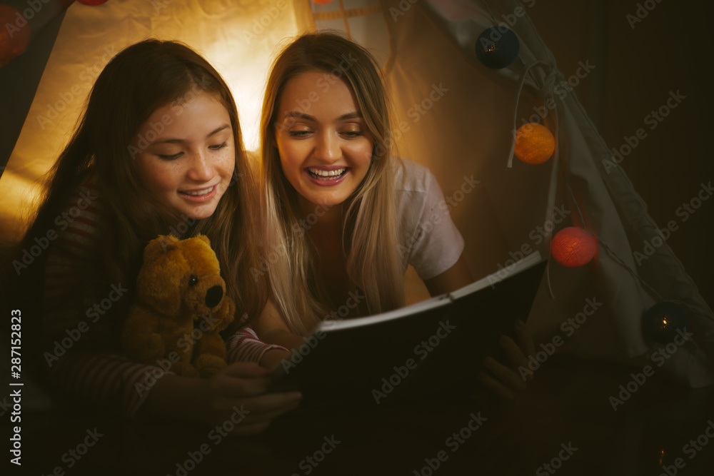 母亲睡前在室内给女儿读书