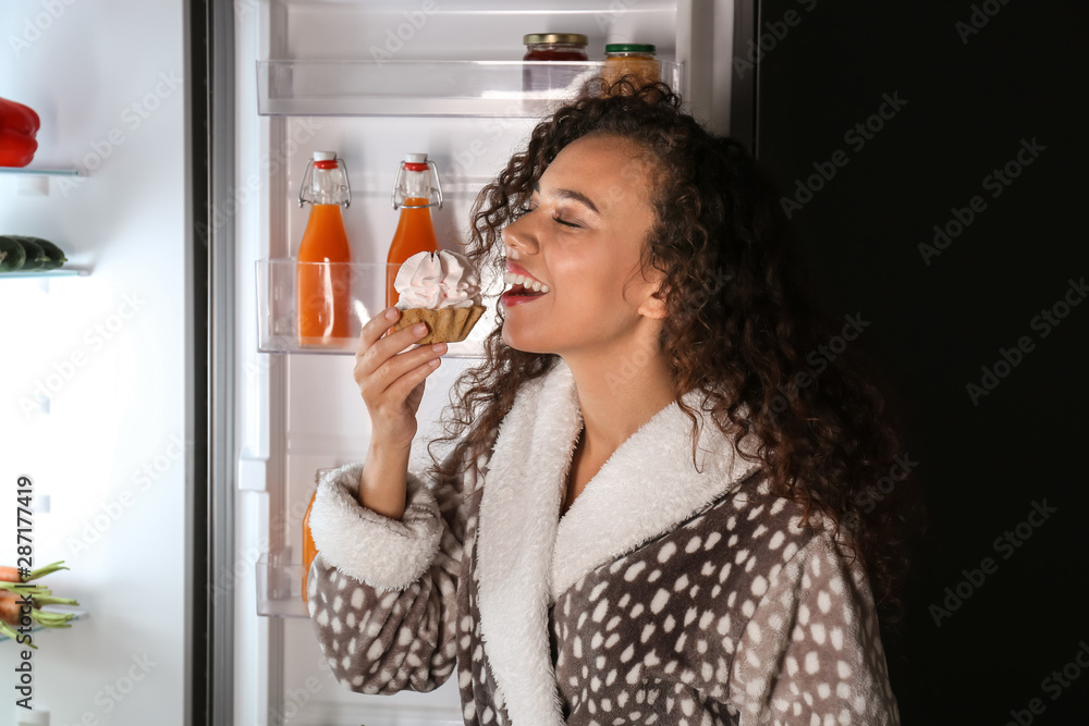 晚上在冰箱附近吃美味蛋糕的快乐女人