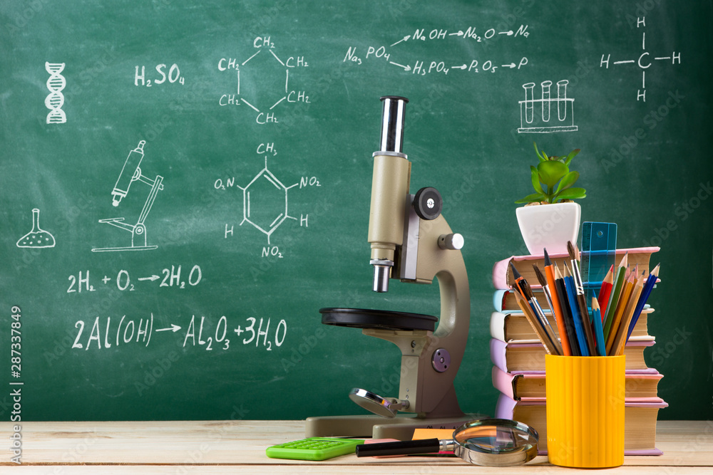 教育与科学概念——教室木桌上的一组彩色书籍和显微镜