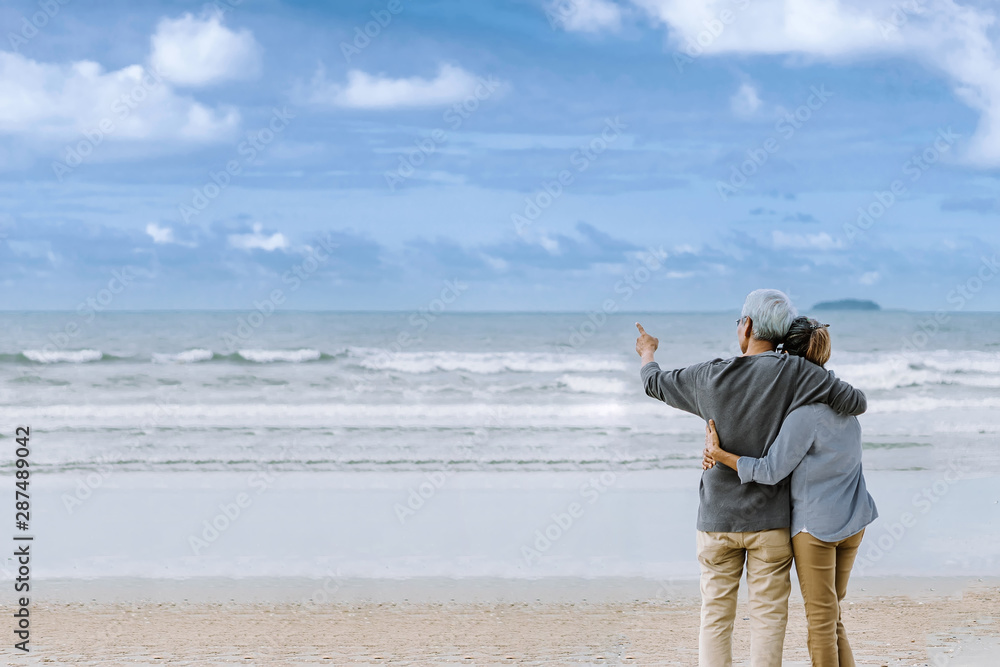 亚洲老年夫妇或老年人周末度假时在海滩散步和坐着