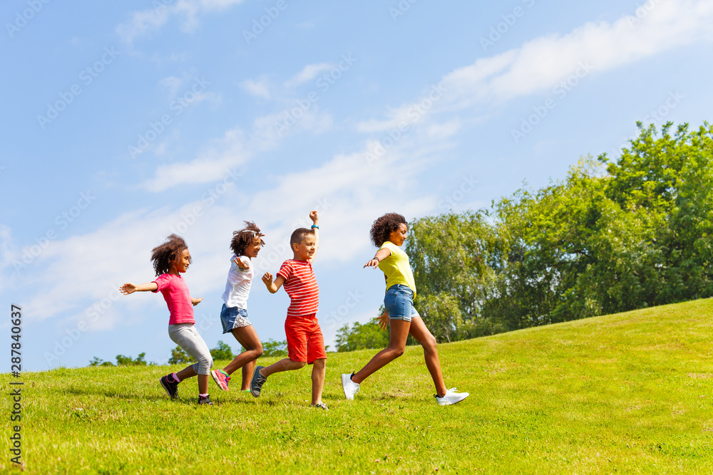 公园草坪上奔跑的儿童团体侧视图