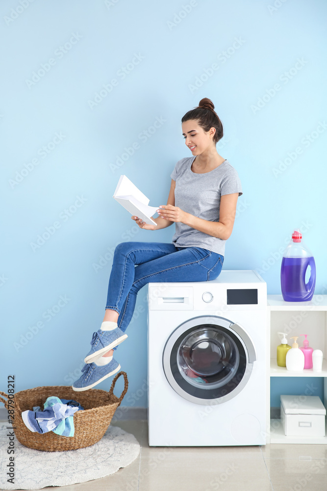 美丽的年轻女子在家洗衣服时看书