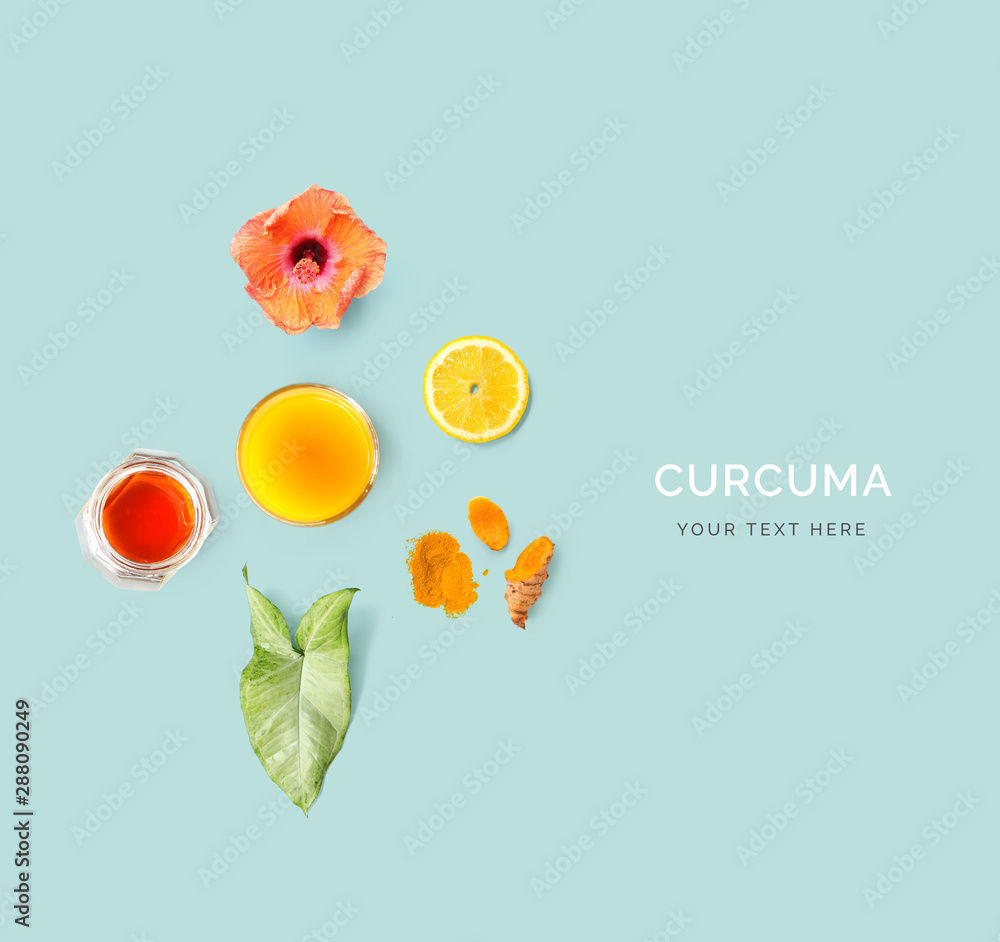由姜黄、蜂蜜、柠檬、花朵和姜黄饮料在蓝色背景上制成的创意布局。平躺