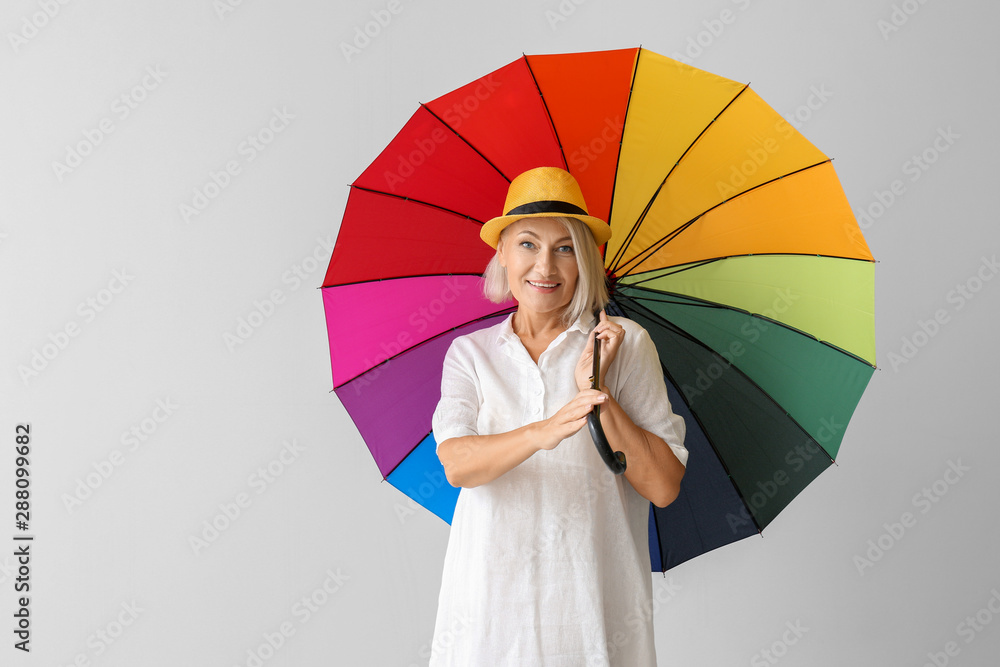 浅色背景带伞的时尚成熟女性