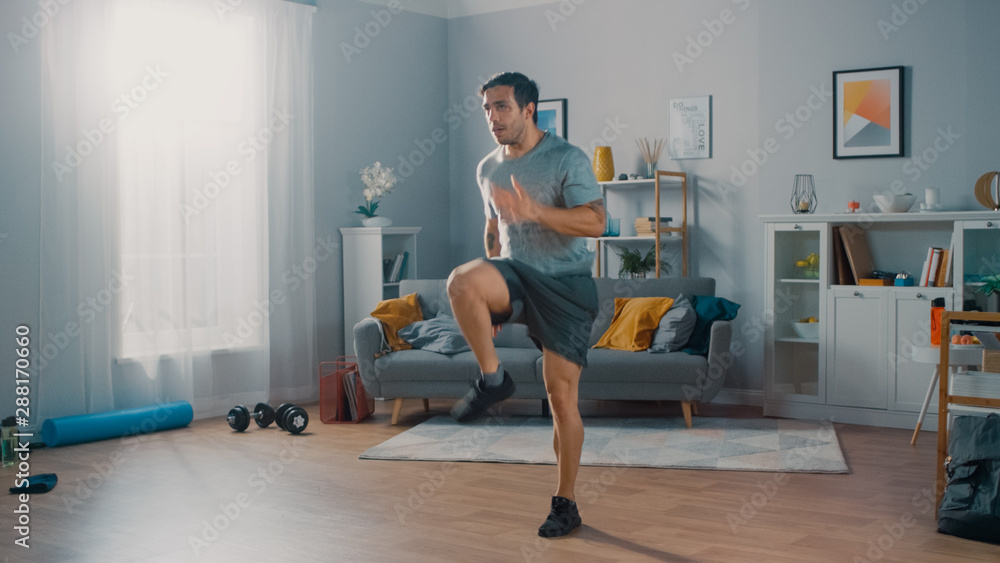 穿着T恤和短裤的强壮运动型男子穿着Spaci在家里精力充沛地慢跑
