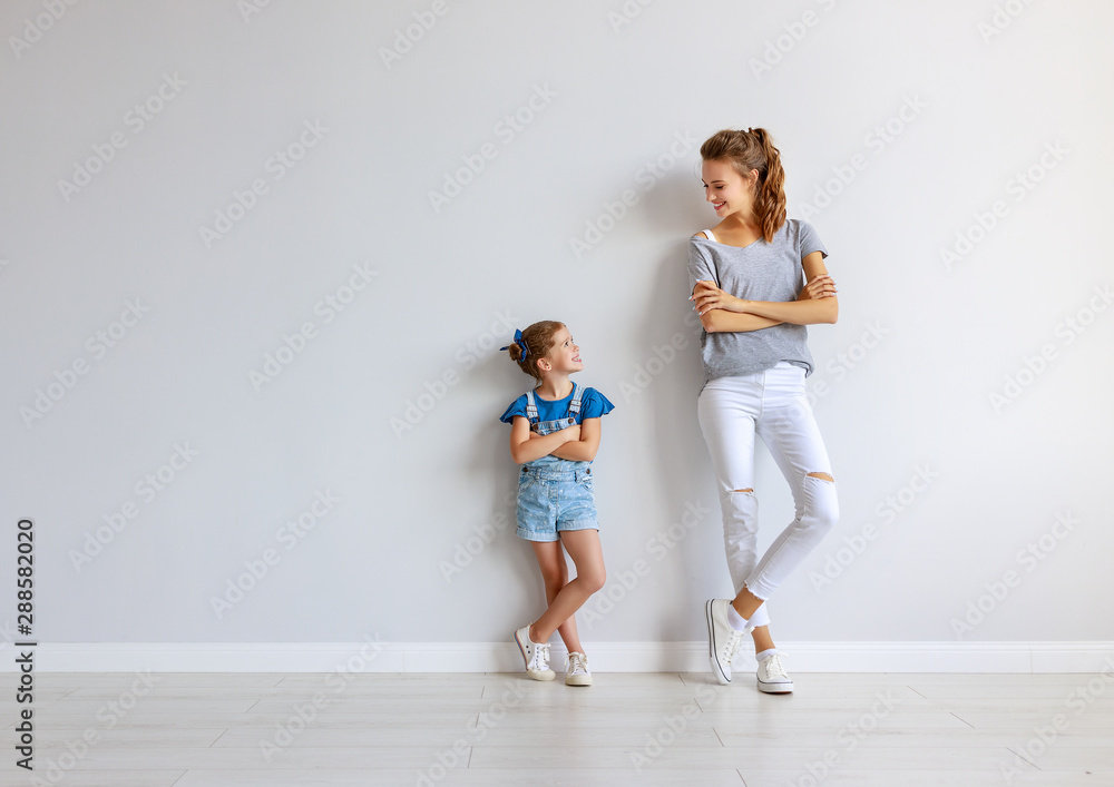 happy family mother (big sister) and child daughter near an empty wall