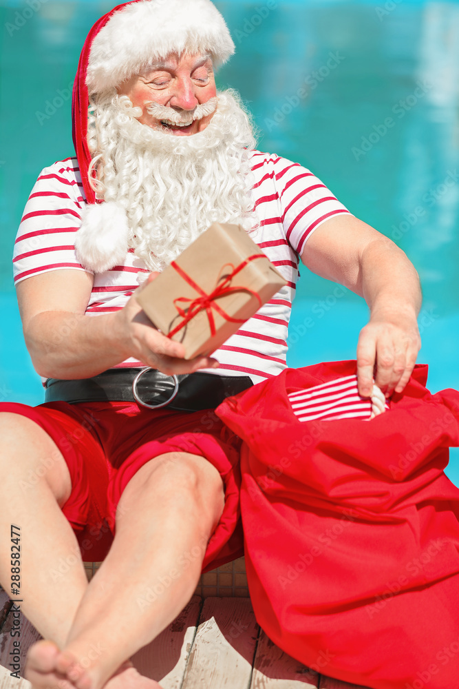度假酒店游泳池附近的圣诞老人带着礼物