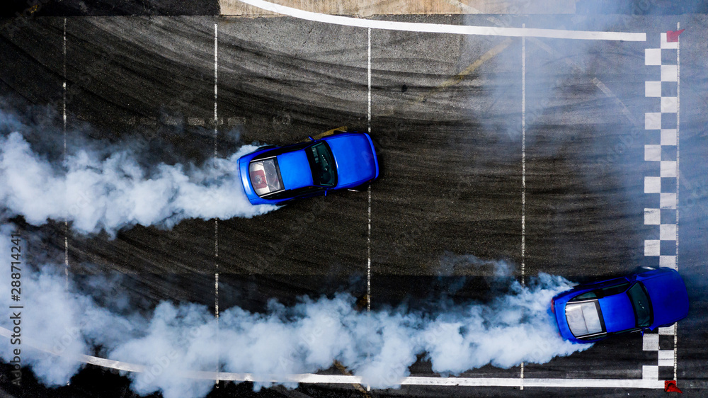 鸟瞰图两辆汽车在沥青赛道上漂移，轮胎燃烧产生大量烟雾