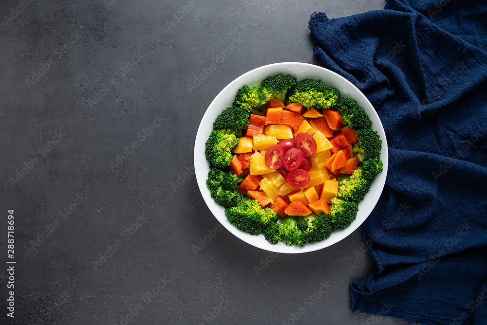 A plate of nutritious delicious fruit and vegetable salad on a black background