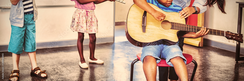 老师在课堂上帮助孩子们演奏乐器