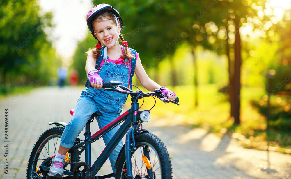 快乐快乐的小女孩在大自然的公园里骑自行车