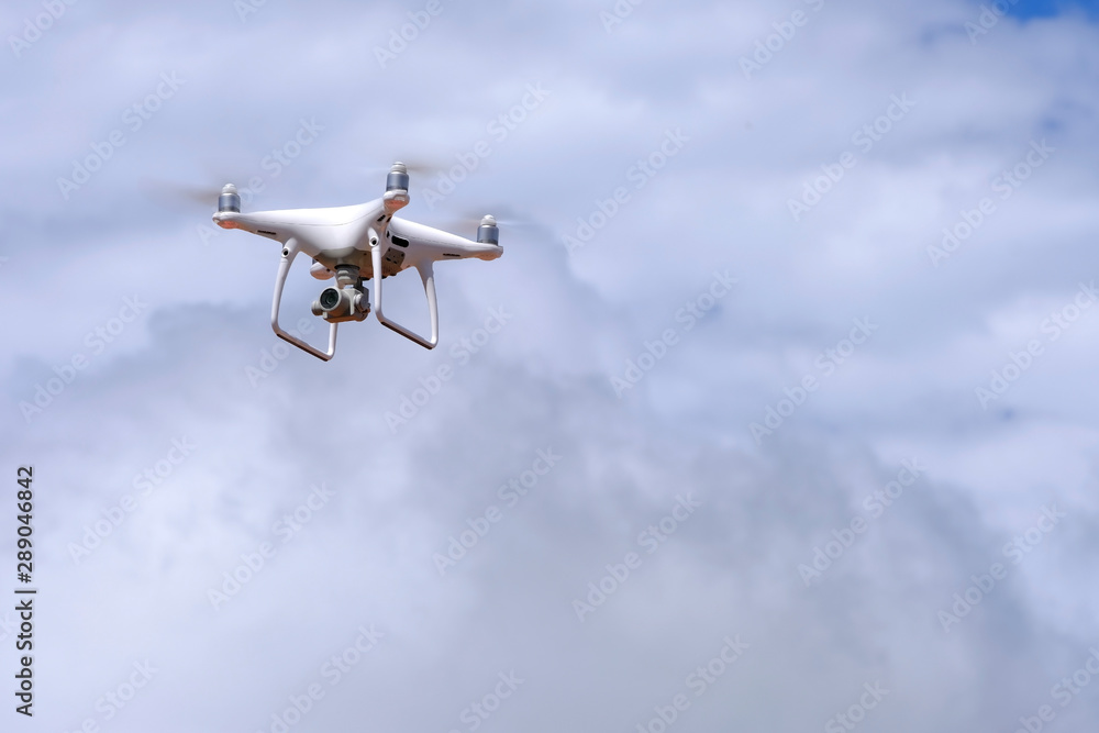 白色无人机四旋翼机在空中飞行，拍摄白色多云背景的照片和视频。