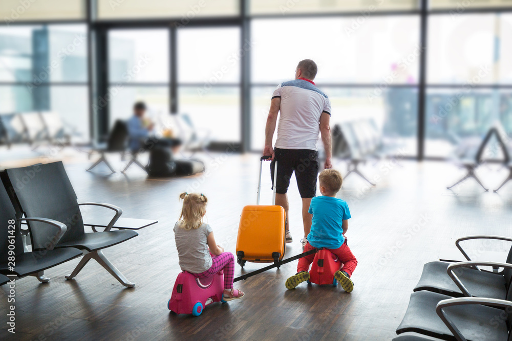 父亲带着两个孩子在机场航站楼一起度假