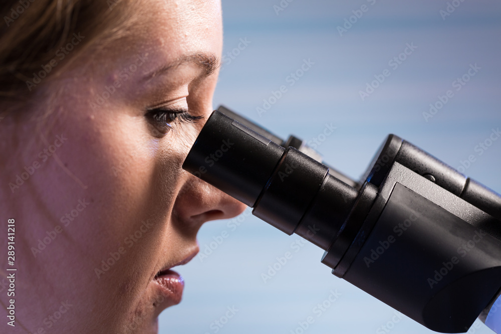 美丽的理科学生在实验室里看着显微镜