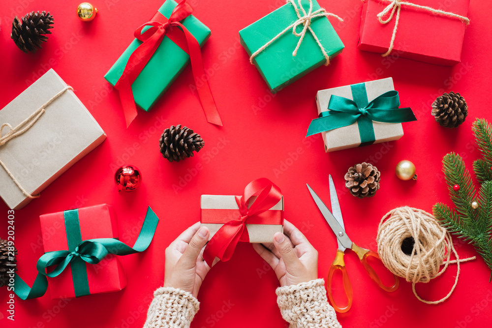 红色背景的手持礼品/礼品盒，用于庆祝圣诞节和新年快乐的概念。俯视图
