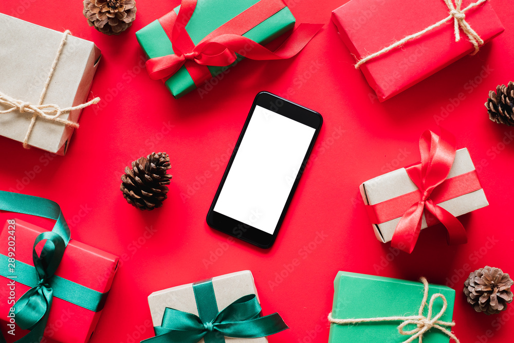 手机，带有红色背景的礼物/礼品盒，用于圣诞节和新年快乐的概念。