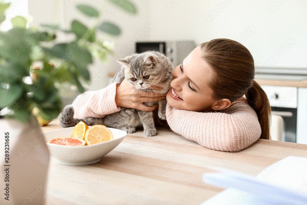 美丽的年轻女人和可爱的猫在厨房