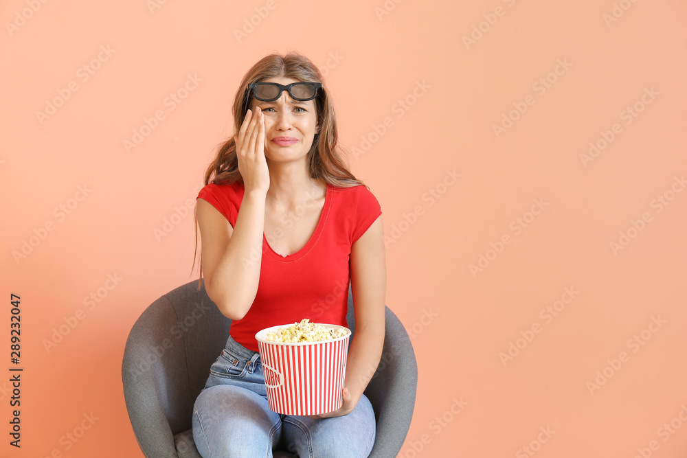 哭泣的女人拿着爆米花在彩色背景下看电影