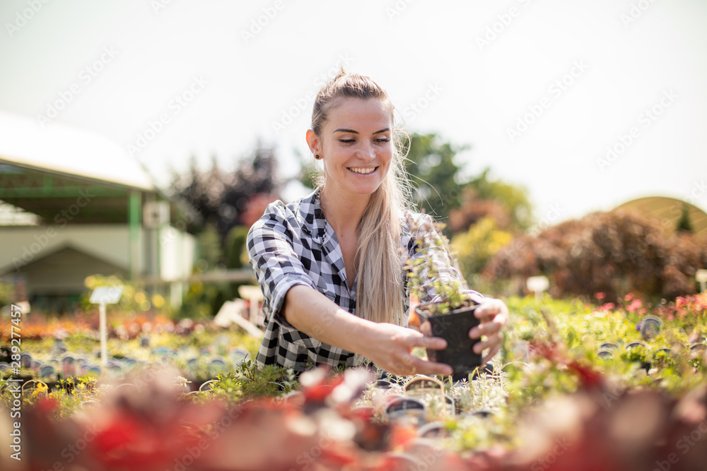 Smiling customer woman in garden center looking for a plants