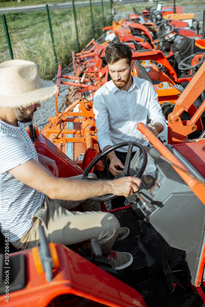 年轻的农学家和优雅的推销员在农业的开阔地上选择拖拉机耕种