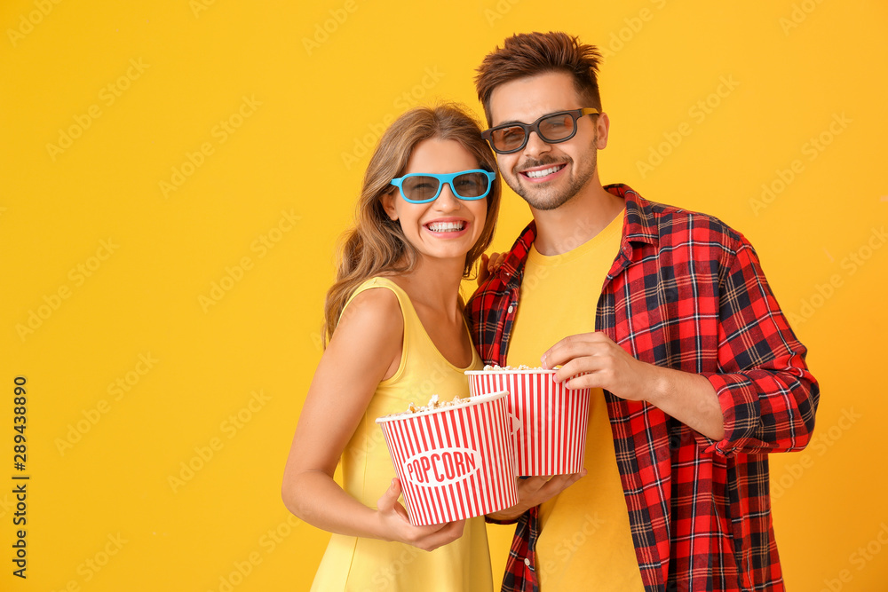 年轻夫妇拿着爆米花在彩色背景下看电影