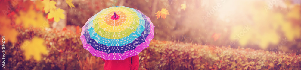 秋天的男孩在雨中撑着五颜六色的伞