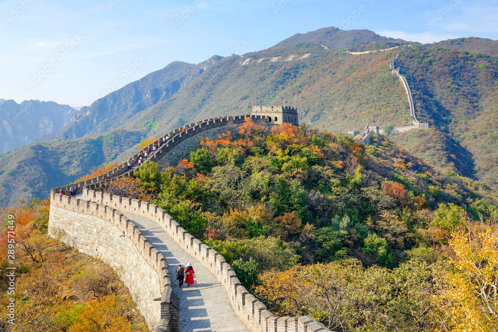 在一个阳光明媚的秋日，游客沿着中国古老的长城行走。