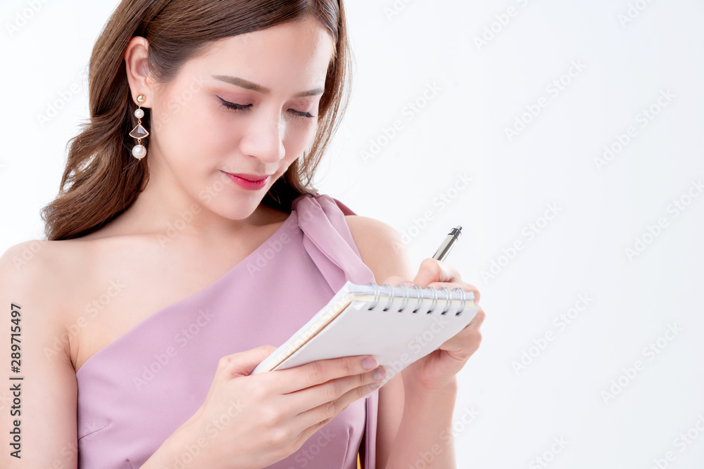 美丽优雅的亚洲女性粉色连衣裙手拿纸笔记和铅笔思考概念whi