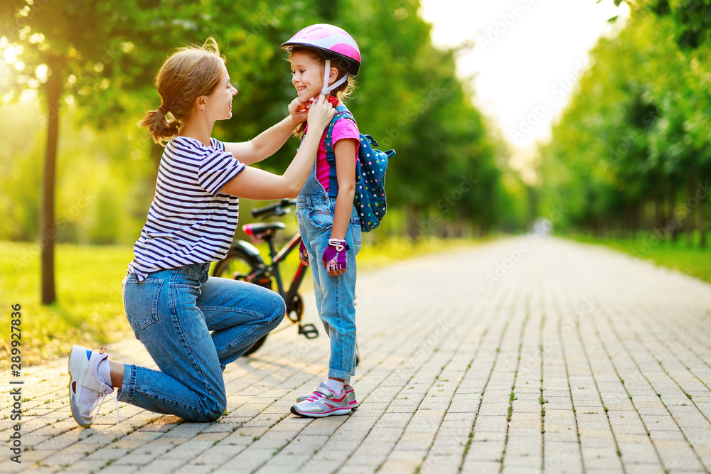 幸福的家庭母亲在公园里教孩子女儿骑自行车。