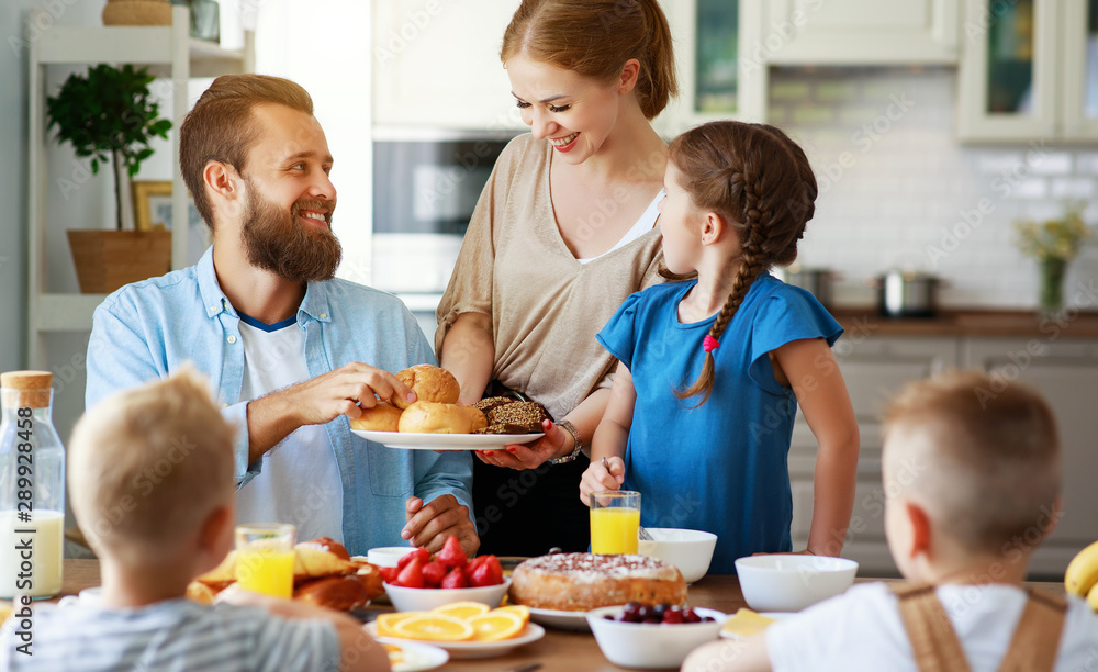 家庭母亲父亲和孩子早上在厨房吃早餐。