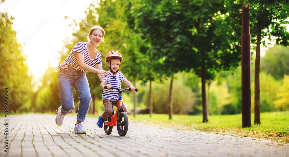 快乐的家庭妈妈教孩子儿子在公园里骑自行车