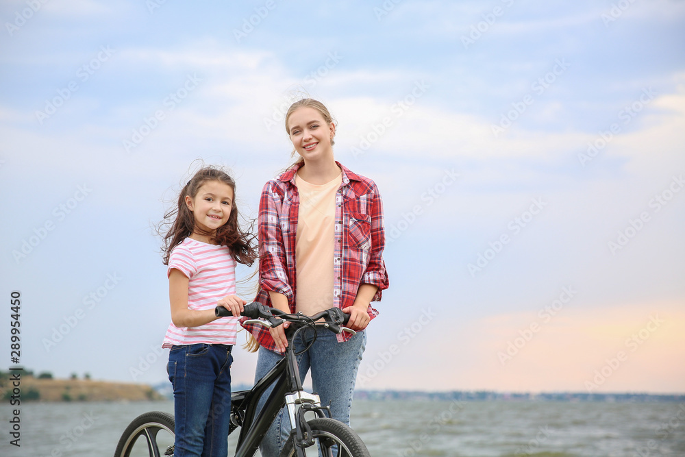 河边骑自行车的妇女和她的小女儿