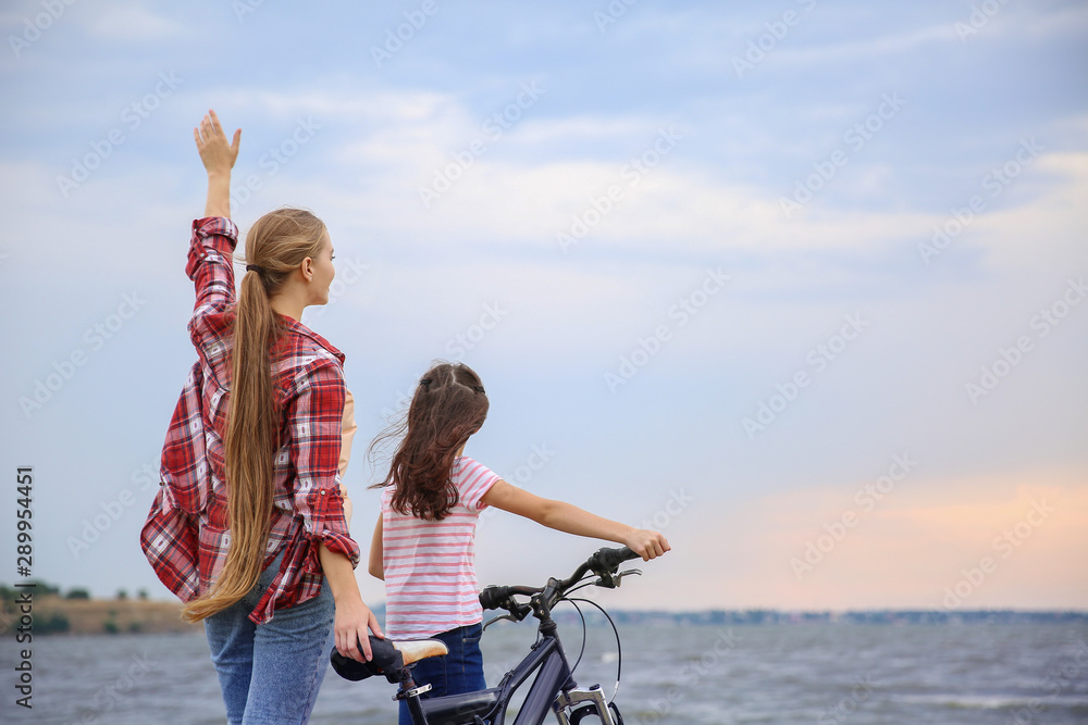 河边骑自行车的妇女和她的小女儿