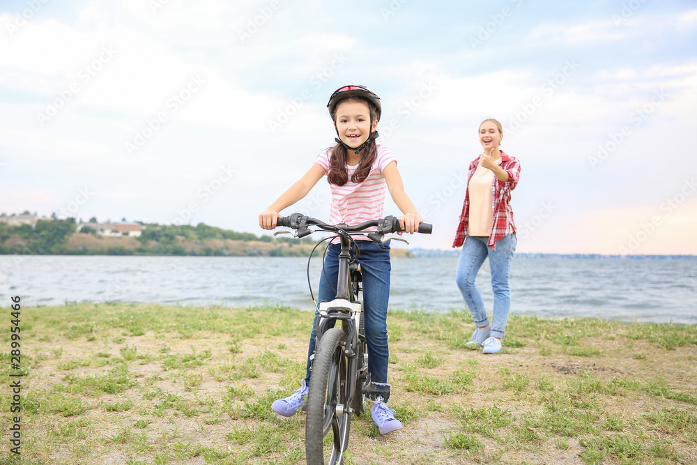 母亲为女儿在户外学会骑自行车感到骄傲