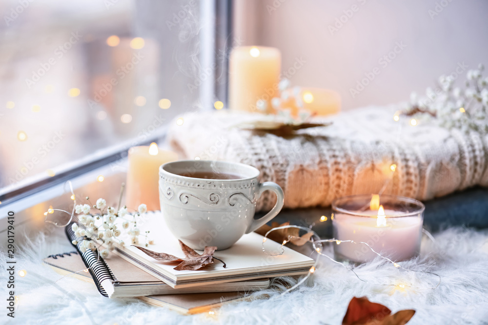 美丽的秋天构图，窗台上有燃烧的蜡烛和一杯茶