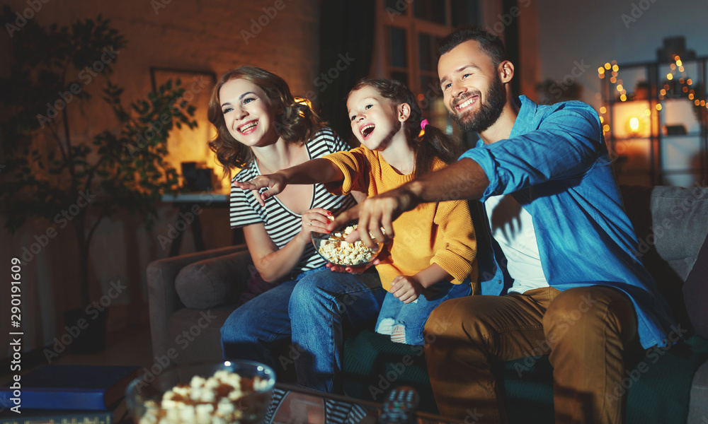 family mother father and child daughter watching projector, TV, movies with popcorn in   evening   a