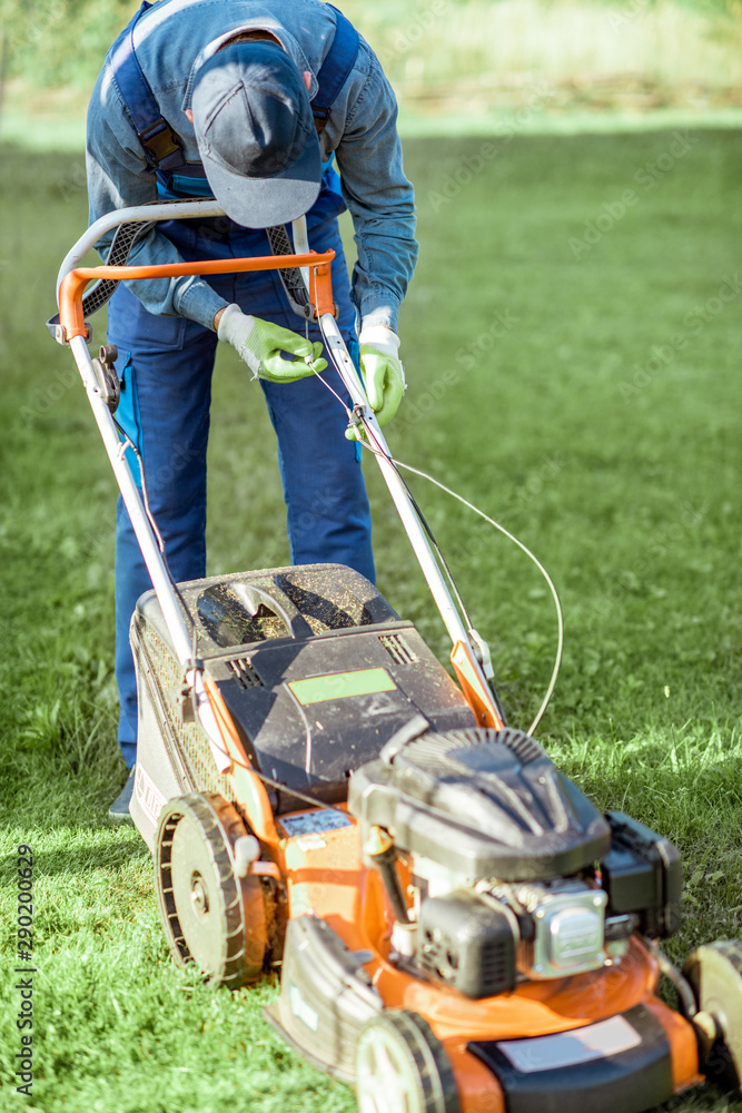 专业园丁在后院割草时修理汽油割草机