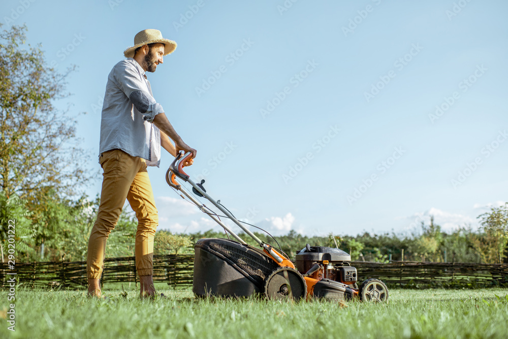 英俊男子穿着休闲，用汽油割草机割草，在t上享受园艺过程