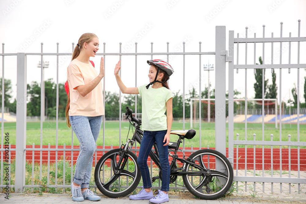 母亲和她的小女儿骑着自行车在户外互相击掌