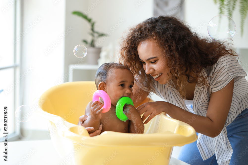 年轻的非裔美国母亲在家给孩子洗澡
