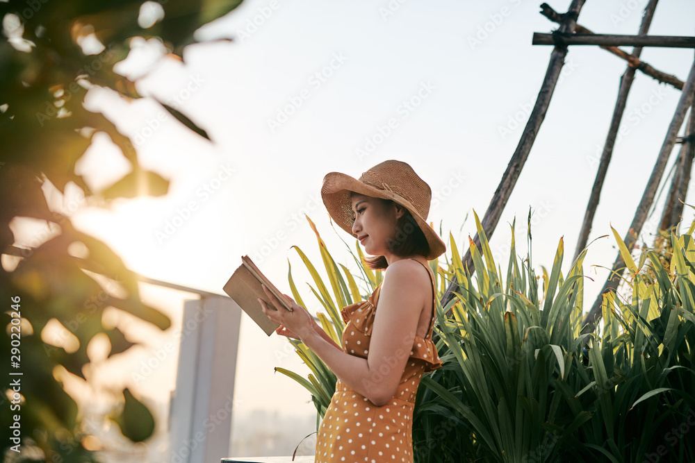 年轻的亚洲女孩在夏日阳光下在大自然中阅读