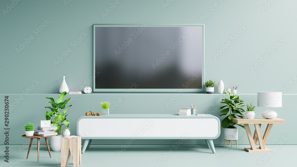 现代客厅橱柜上的电视在绿色墙壁背景上有植物和书籍。