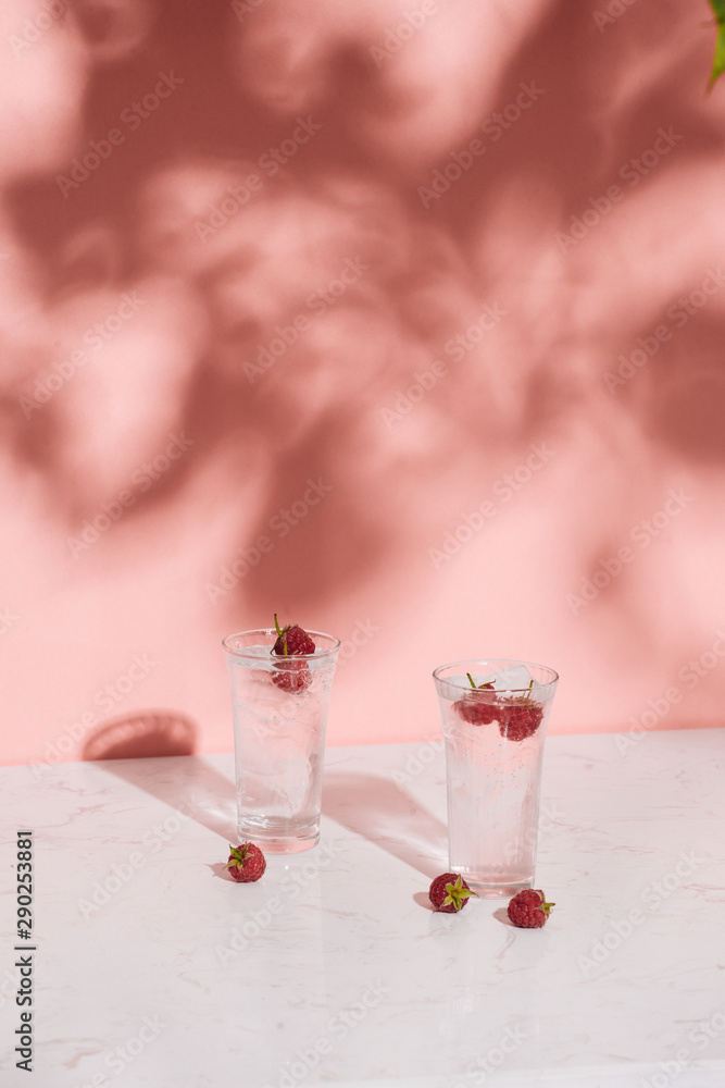 Glass of cold raspberry cider with fresh berries on light background